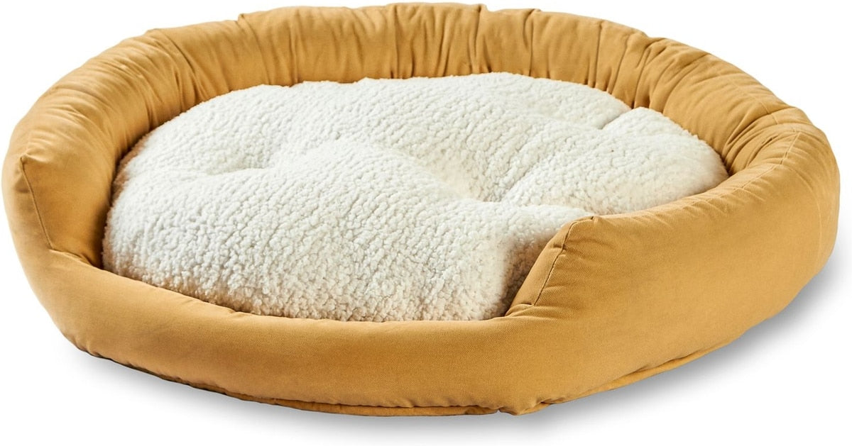 Round pet bed with beige exterior and white interior on a white background