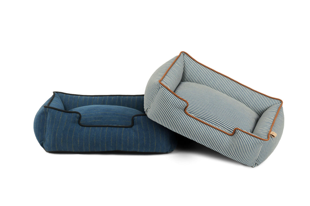 Two pet beds, one blue and one gray with brown trim, on a white background.