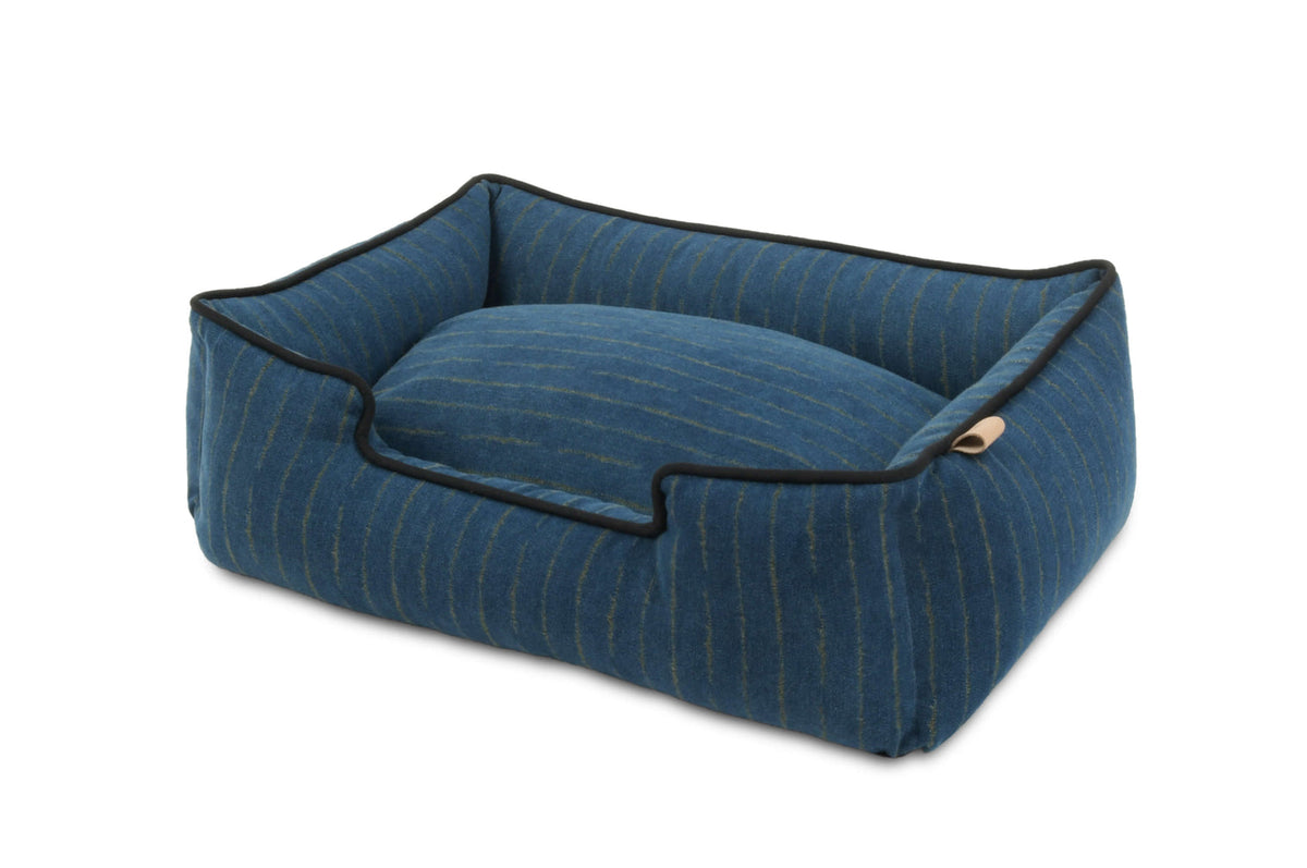 Blue pet bed with black piping on a white background