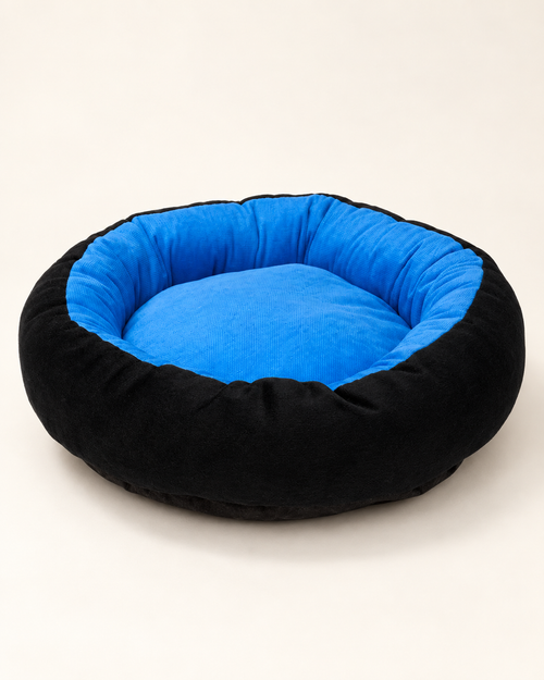 A round pet bed with a black plush exterior and a bright blue velvet interior, photographed on a clean off-white background.
