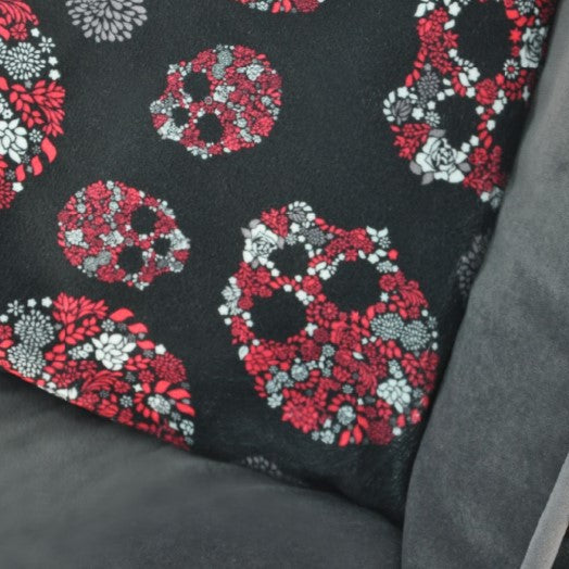 Textile with floral skull pattern on black fabric, featuring a brand label.