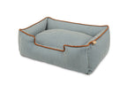 Pet bed with blue and white striped pattern and brown trim on a white background