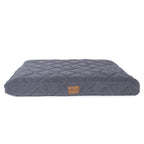 Quilted blue pet bed with a brown label on a beige background