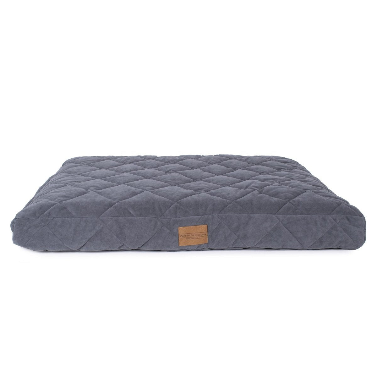 Quilted blue pet bed with a brown label on a beige background